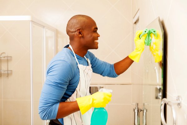 Cheerful man cleaning bathroom at home.