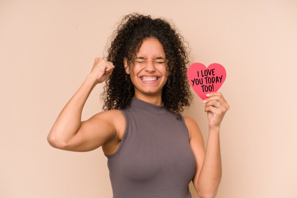 Woman holding a heart after Valentine's Day with raising fist showing victory.